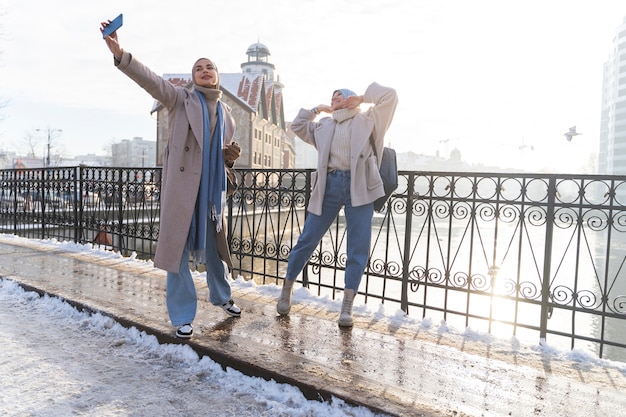 Dos mujeres musulmanas con hijabs tomándose un selfie mientras viajaban por la ciudad