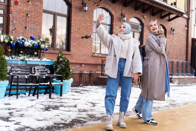 Dos mujeres musulmanas con hijabs tomándose una selfie mientras viajan