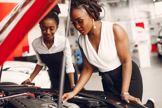 Dos mujeres negras con estilo en un salón de autos