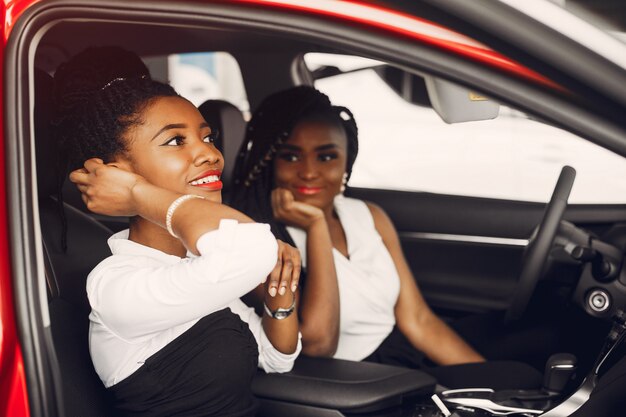 Dos mujeres negras con estilo en un salón de autos