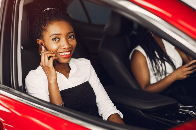 Dos mujeres negras con estilo en un salón de autos