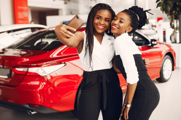 Dos mujeres negras con estilo en un salón de autos