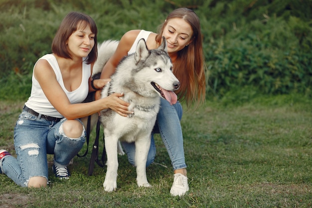 Dos mujeres en un parque de primavera jugando con lindo perro