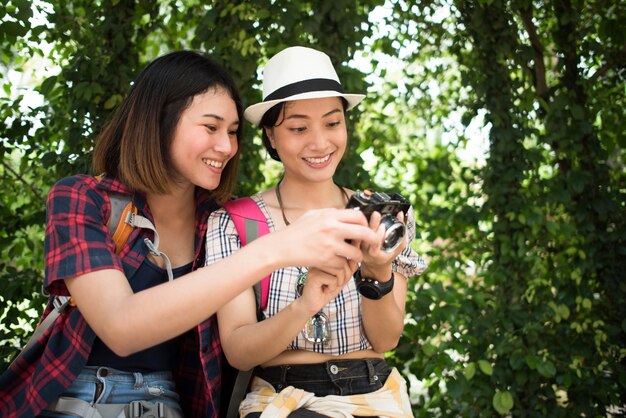 Dos de las mujeres pasándola bien mientras estaban sentadas en una sucursal después de caminar a través de lo urbano.