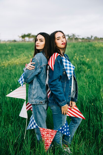 Dos mujeres posando en la hierba verde que mira la cámara