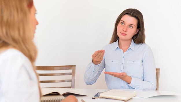 Dos mujeres que usan lenguaje de señas para comunicarse.