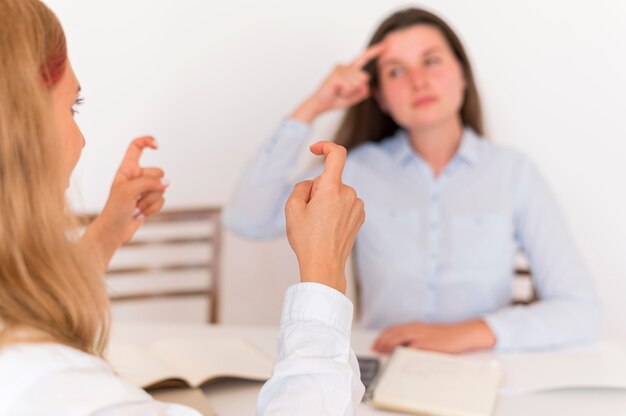 Dos mujeres que usan lenguaje de señas para conversar.