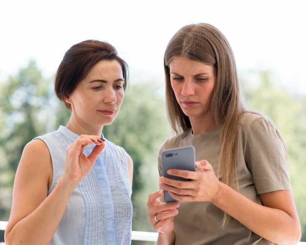 Foto gratuita dos mujeres que utilizan el lenguaje de señas y el teléfono inteligente para comunicarse