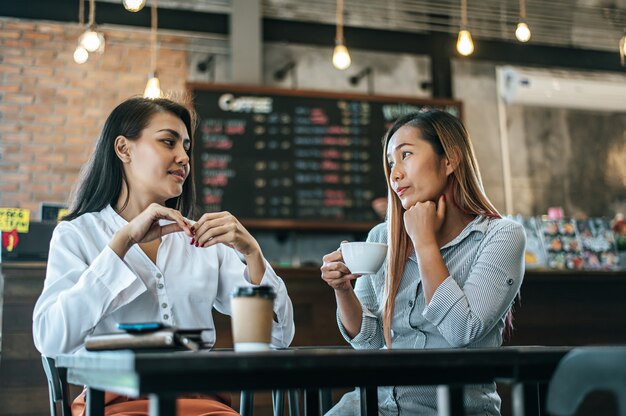 Dos mujeres sentadas y tomando café y charlando en una cafetería