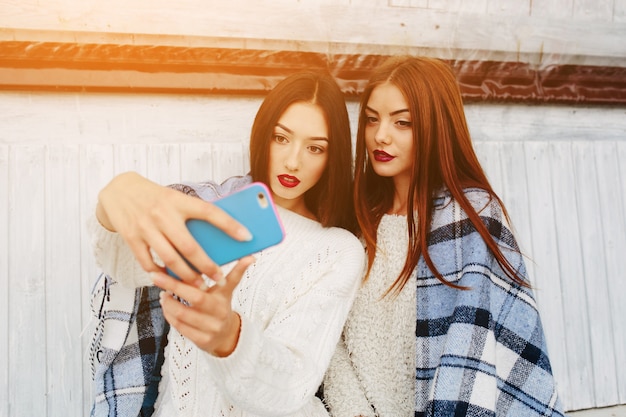 Dos mujeres se sientan en el banco y hacen selfie