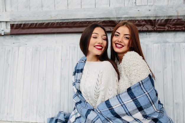 Dos mujeres se sientan en un banco en el parque y posando