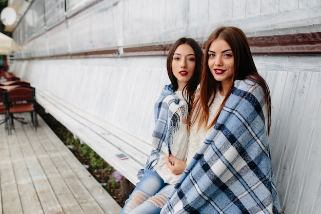 Dos mujeres se sientan en un banco en el parque y posando