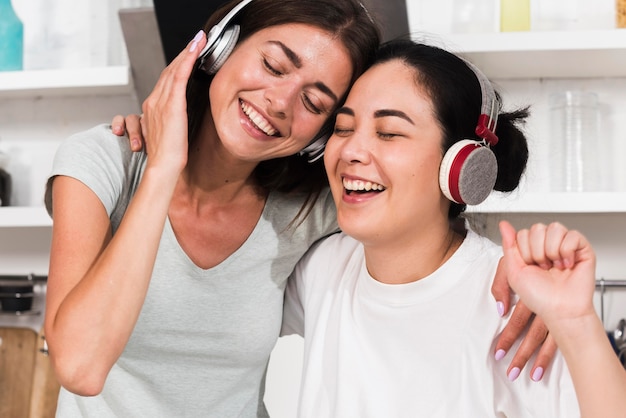 Dos mujeres sonrientes cantando música en auriculares