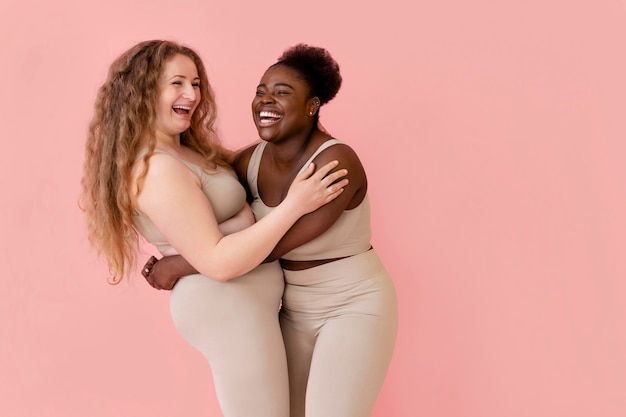 Foto gratuita dos mujeres sonrientes posando mientras usa un modelador de cuerpo