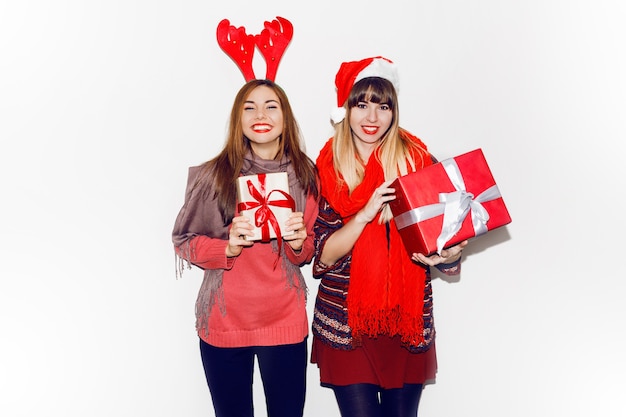 Dos mujeres sonrientes con regalos de año nuevo. Usando lindos sombreros de mascarada. Sonrisa sincera. Celebrando el estado de ánimo. Retrato flash.