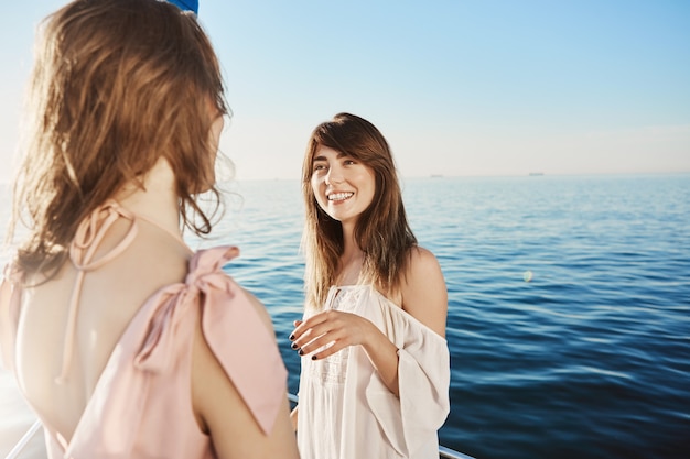 Dos mujeres en yate navegando en el mar, conversando sobre sus grandes planes de vacaciones.