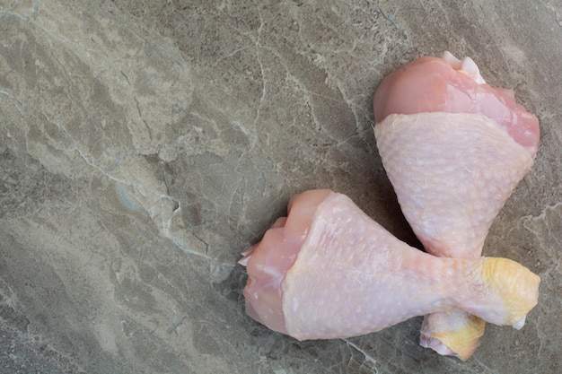 Dos muslos de pollo crudo sobre fondo de mármol. Foto de alta calidad