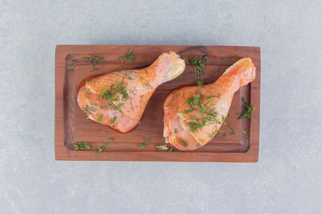 Dos muslos de pollo y rodajas de limón, sobre la superficie azul