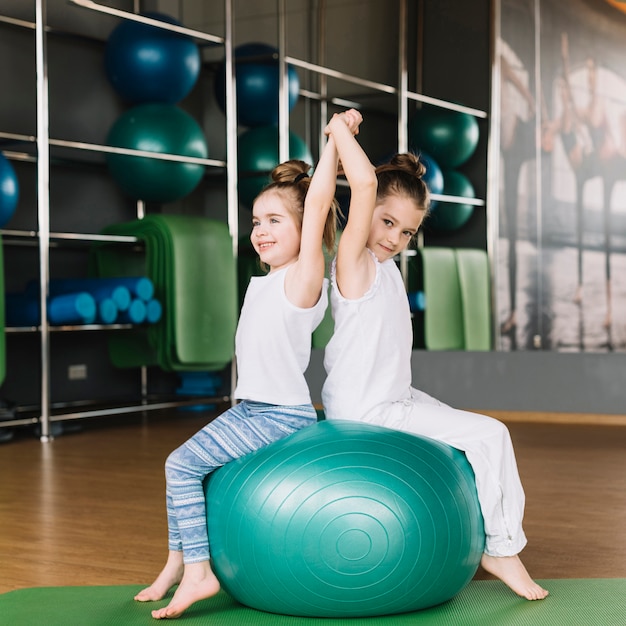 Foto gratuita dos niña sentada de espaldas sobre ejercicio de pelota juntos