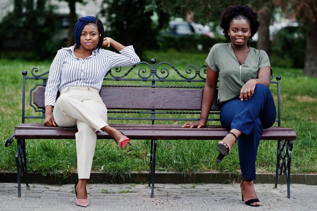 Dos niñas africanas posaron en la calle de la ciudad sentadas en el banco