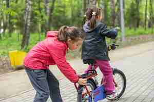 Foto gratuita dos niñas andan en bicicleta en el parque en primavera.