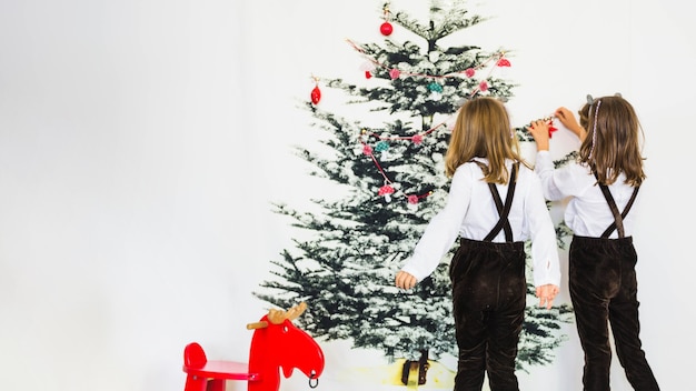 Foto gratuita dos niñas decorando árbol de navidad