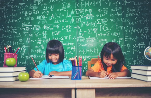 Dos niñas con dibujo de lápices de colores en la lección en el aula