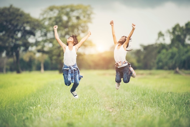 Dos niñas felices saltan en el parque natural