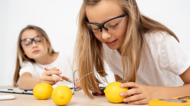 Dos niñas haciendo experimentos científicos con electricidad y limones.