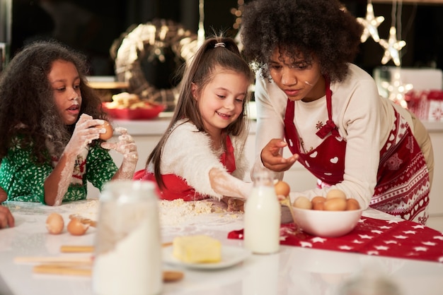 Dos niñas haciendo galletas con mamá en Navidad