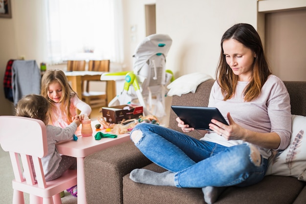 Foto gratuita dos niñas jugando cerca de su madre usando tableta digital