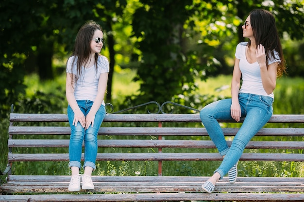 Dos niñas llevaba gafas de sol sentado en el banco