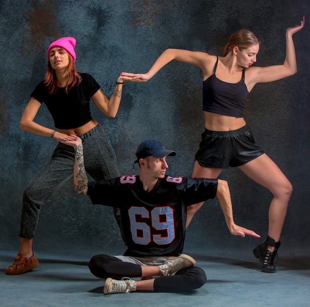 Las dos niñas y un niño bailando hip hop en el azul