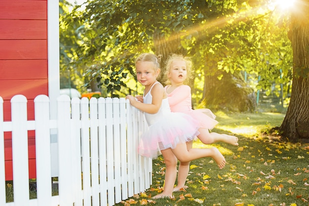 Las dos niñas en el patio de recreo contra parque o bosque verde