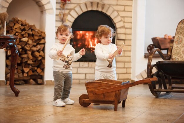 Las dos niñas de pie en casa contra la chimenea