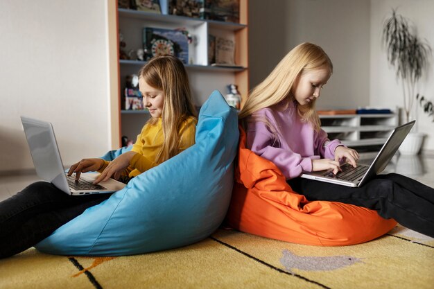 Dos niñas que usan computadoras portátiles y trabajan juntas