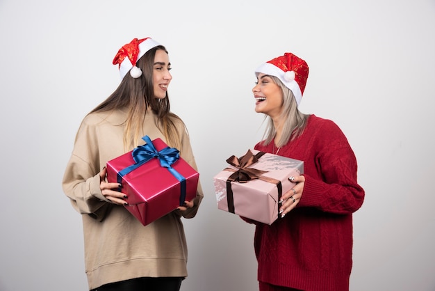 Dos niñas sonrientes con sombrero de Santa con regalos de Navidad festivos.