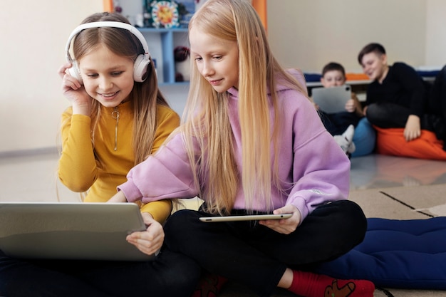 Dos niñas trabajando juntas usando su computadora portátil y tableta