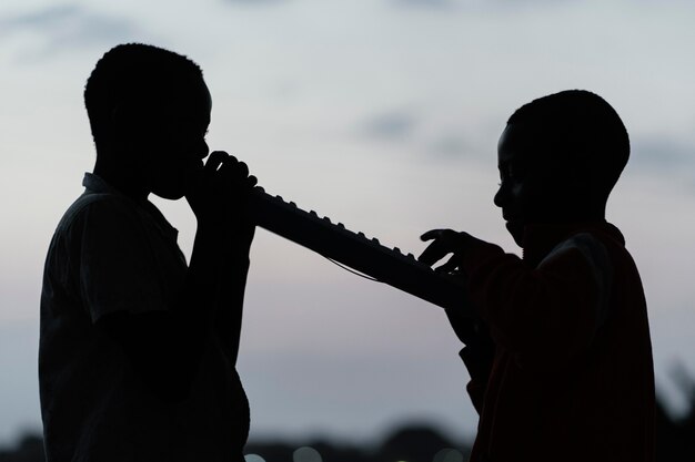 Dos niños africanos al atardecer tocando el instrumento