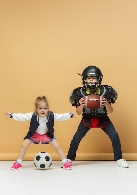 Dos niños felices y hermosos muestran deporte diferente.