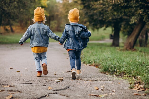 Dos niños hermanos corriendo en un parque de otoño