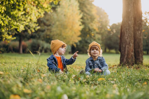 Dos niños hermanos sentados en la hierba bajo el árbol