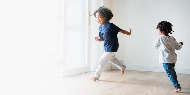 Dos niños negros jugando y persiguiéndose en un espacio en blanco de la habitación vacía