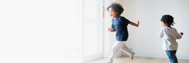 Foto gratuita dos niños negros jugando y persiguiéndose en un espacio de texto de habitación vacía