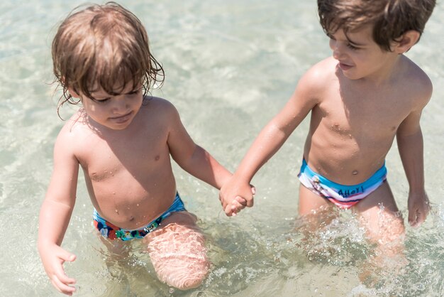 Dos niños tomados de la mano en el mar