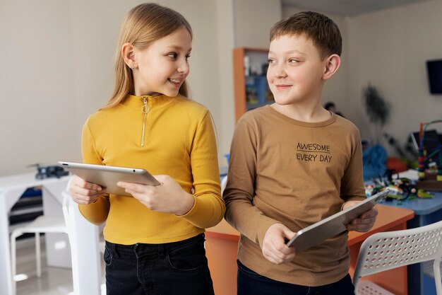 Dos niños usando tabletas y trabajando juntos