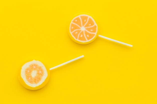 Foto gratuita dos paletas de cítricos sobre fondo amarillo