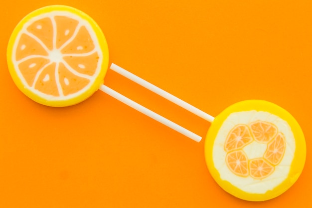 Dos paletas de cítricos sobre fondo naranja