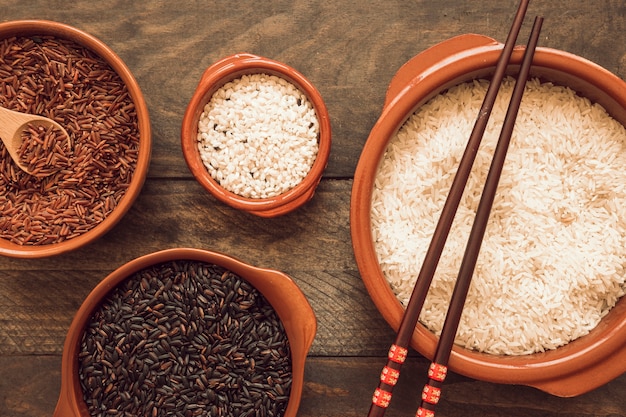 Dos palillos en cuencos de arroz sobre la mesa de madera