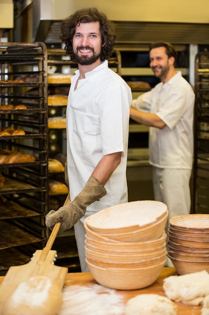 Dos panaderos sonriente que prepara el pan en la cocina de la panadería